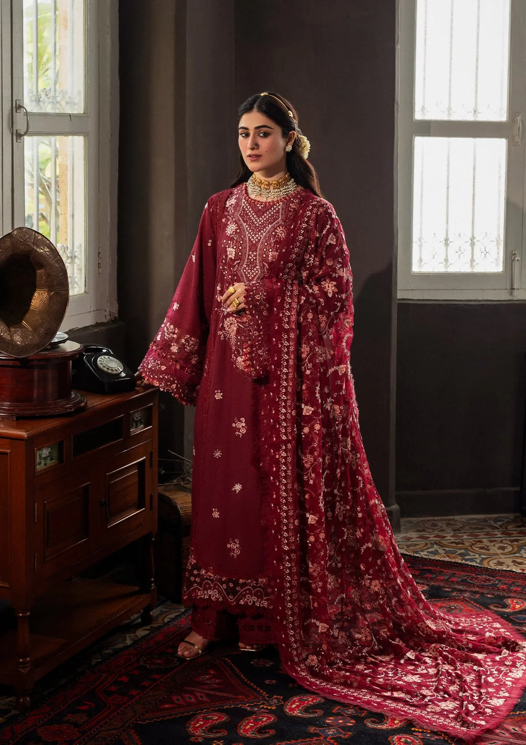 Woman in a red traditional outfit standing in a room with vintage decor.
