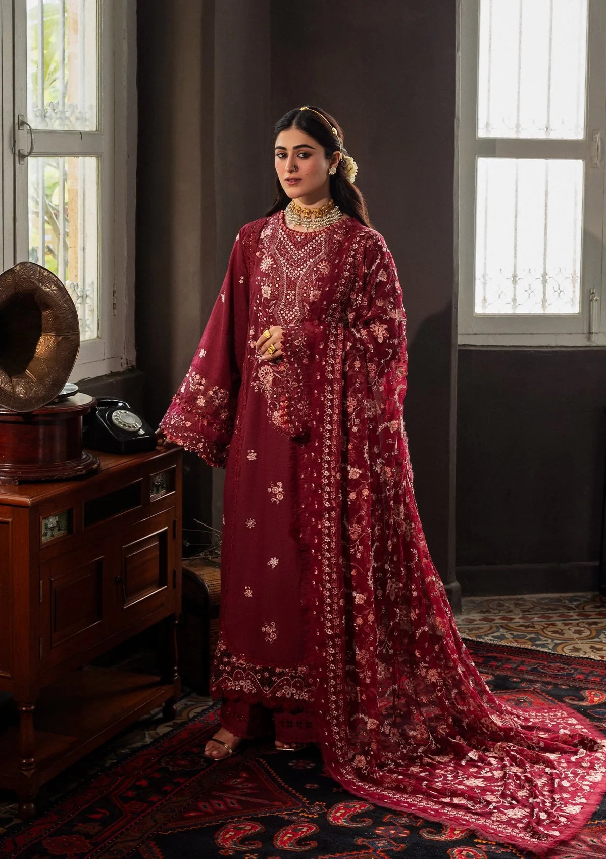 Woman in a red traditional outfit standing in a room with vintage decor.
