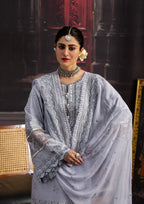 Woman in a grey traditional outfit with jewelry against a dark background