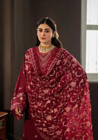 Woman wearing a red traditional outfit with intricate patterns indoors.